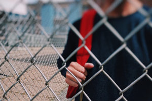 ragazzo con zanno in spalla dietro una rete